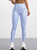 A model wearing high-waisted light blue leggings with a subtle white leopard print pattern, paired with white sneakers, shown from the waist down against a neutral studio background.